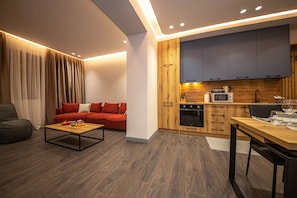 Een moderne woonkamer met een bank, salontafel en een eethoek met een tafel en stoelen.