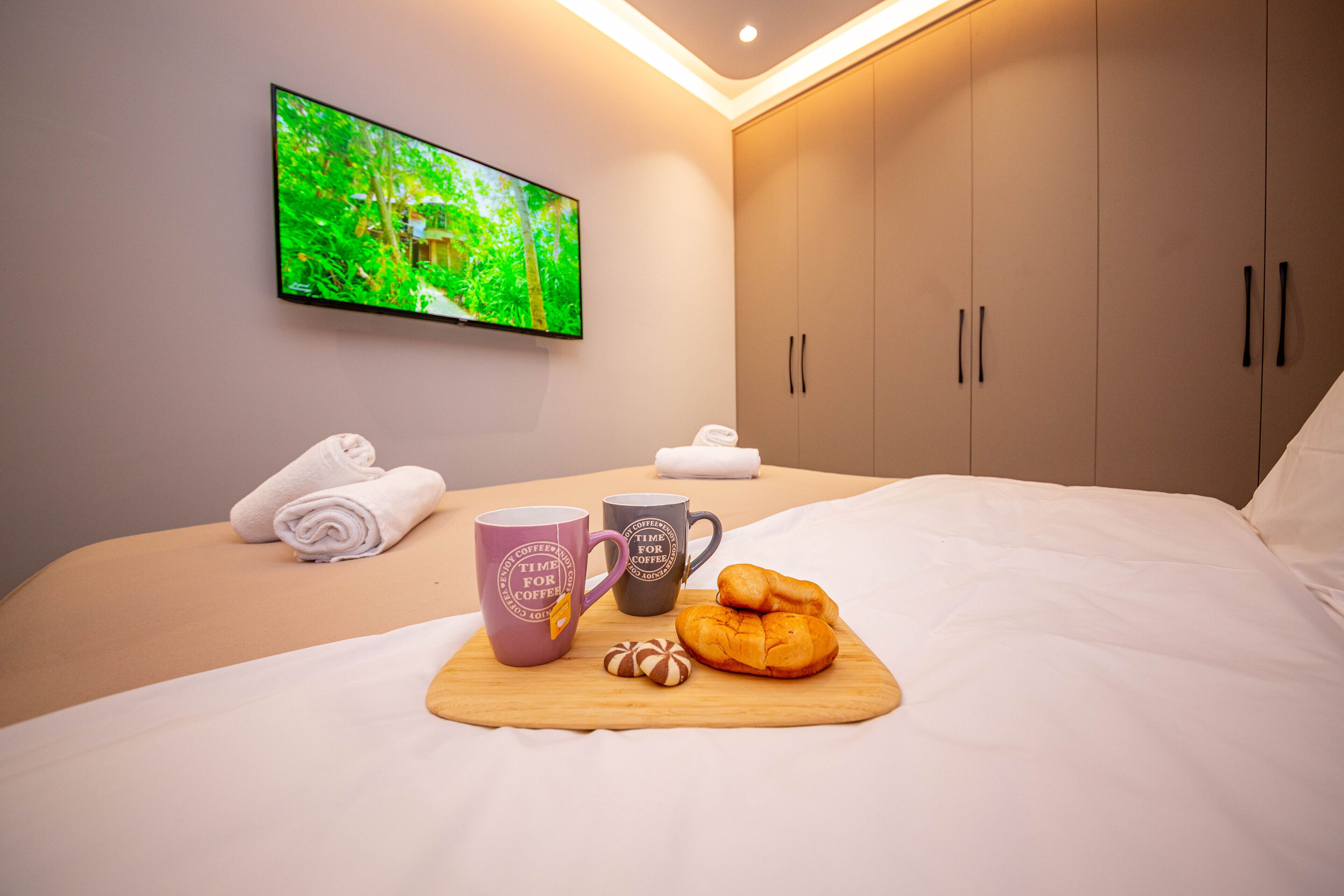 Un lit bien fait, avec un plateau de petit-déjeuner, deux tasses et un croissant.