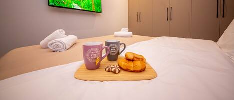 Un lit bien fait, avec un plateau de petit-déjeuner, deux tasses et un croissant.