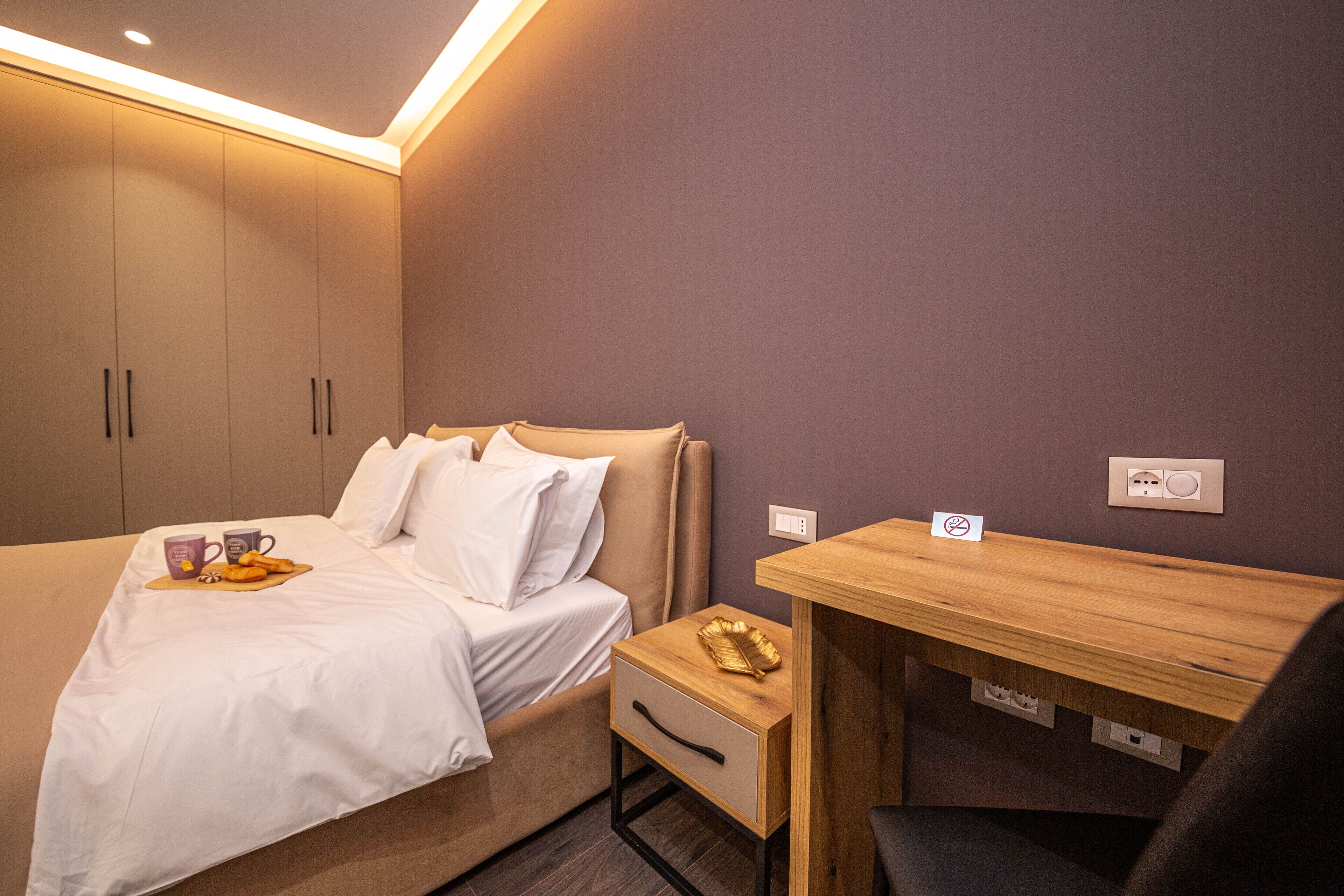 A bedroom with a bed, bedside table, and a small desk with a chair.