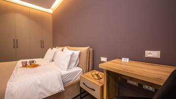 A bedroom with a bed, bedside table, and a small desk with a chair.
