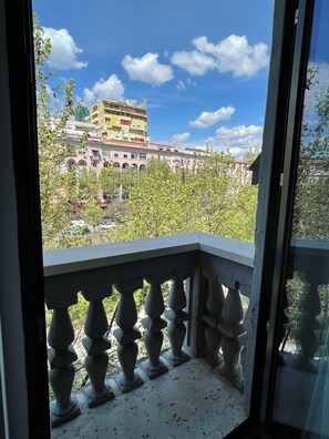 Varanda com vista para um edifício com várias varandas, sob um céu claro.