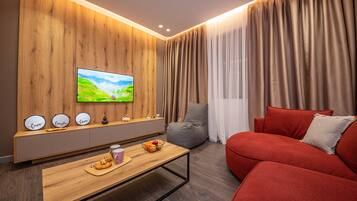 Una sala de estar moderna con una pared de acento de madera, un televisor de pantalla plana, un sofá rojo, una mesa de centro con aperitivos y un asiento informal de forma de saco gris.