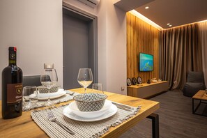 Uma sala de jantar com uma mesa de madeira posta para dois, uma garrafa de vinho e uma tigela com um padrão decorativo.