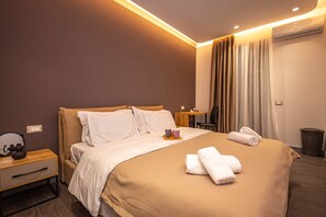 Quarto de hotel com cama, mesa de cabeceira e escrivaninha com cadeira.