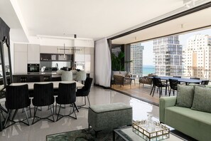 A modern apartment with a kitchen, dining area, and a balcony with a city view. - MAMAD Luxury 2BR with Terrace & Sea View by FeelHome (Tel Aviv - Jaffa)