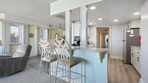 Een moderne keuken met een centraal eiland, barstoelen en een koelkast.