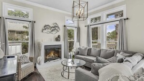 A living room with a fireplace, a sofa, a coffee table, and large windows. - Private Pool-4 bikes (Santa Rosa Beach)