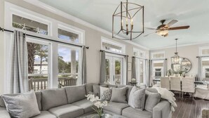 A spacious living room with a large gray sofa, a glass coffee table, and a ceiling fan. - Private Pool-4 bikes (Santa Rosa Beach)