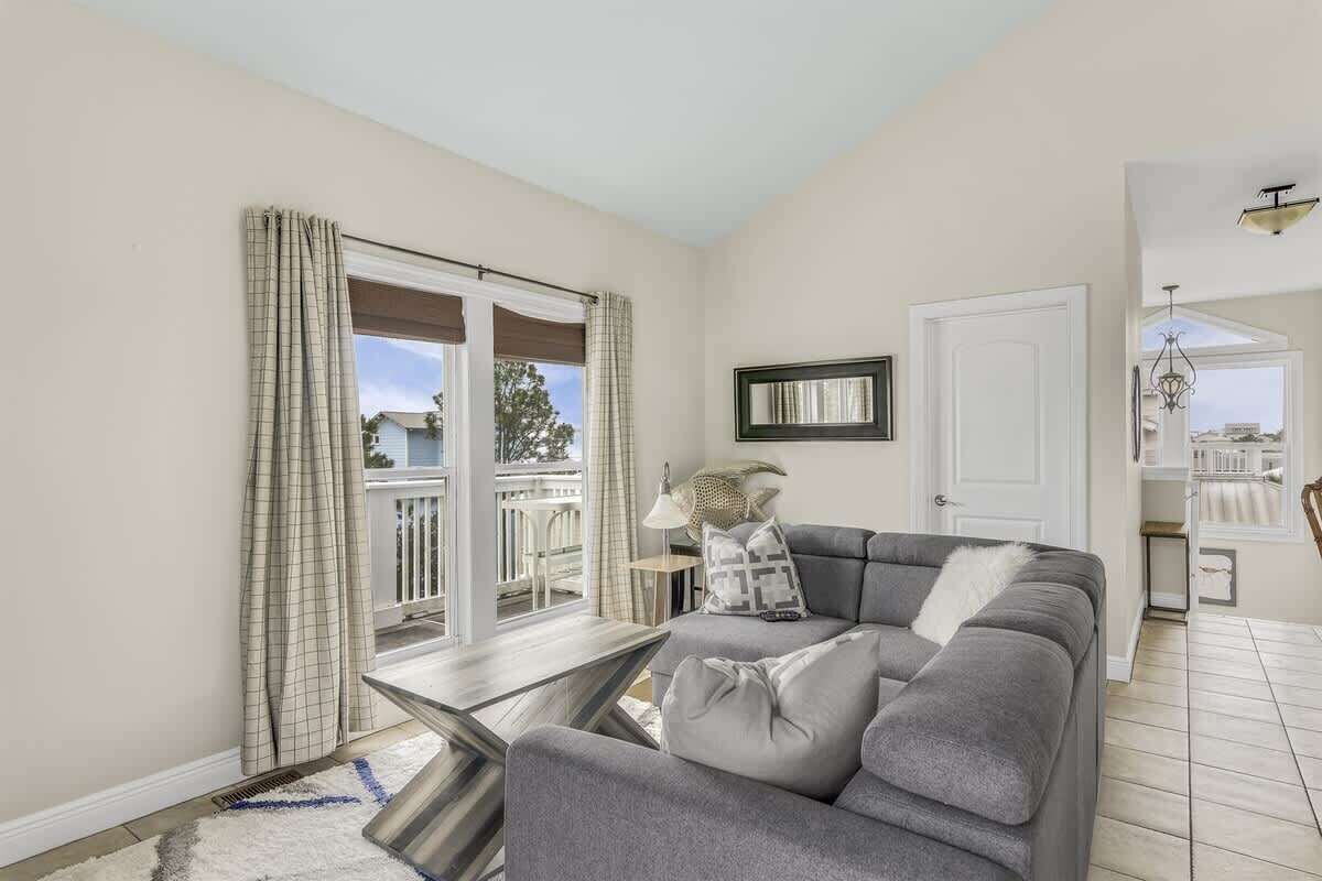 A living room with a grey sofa, a small table, and a view of a balcony.