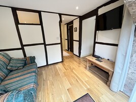 Una sala de estar moderna con piso de madera, un sofá, una mesa de centro y un televisor de pantalla plana montado en la pared.