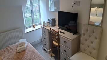 Ein Schlafzimmer mit Bett, Schreibtisch mit Fernseher, Stuhl, Kommode und Fenster mit Blick.