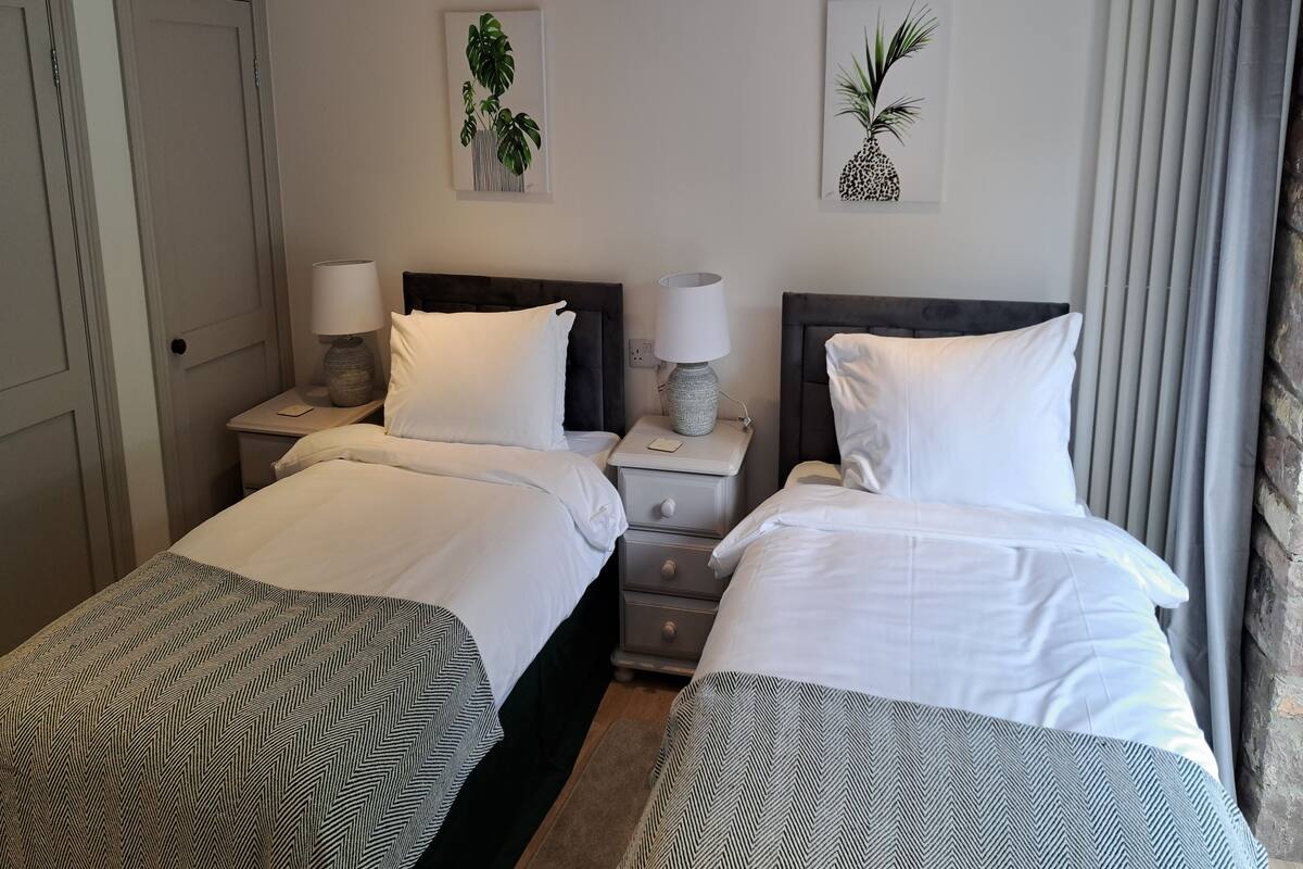 A hotel room with two beds, a nightstand with lamps, and two wall-mounted artworks.