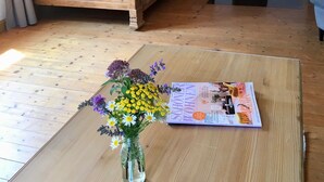 A wooden bed in a room with a fireplace, a vase of flowers, and a magazine on a wooden table. - PrienZeit vacation apartment with fantastic panoramic views (Aschau)