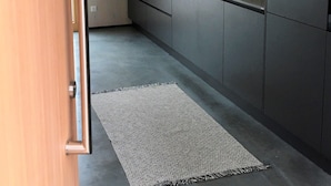 Een moderne keuken met grijze kastjes, een roestvrijstalen spoelbak en een raam boven de spoelbak.