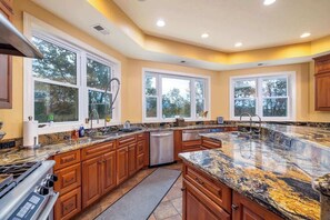 Una cocina moderna con encimeras de granito, armarios de madera y ventanas amplias.