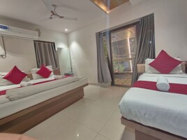 Habitación de hotel con dos camas, un ventilador de techo, un espejo grande y una puerta corrediza de vidrio que da a un espacio exterior.