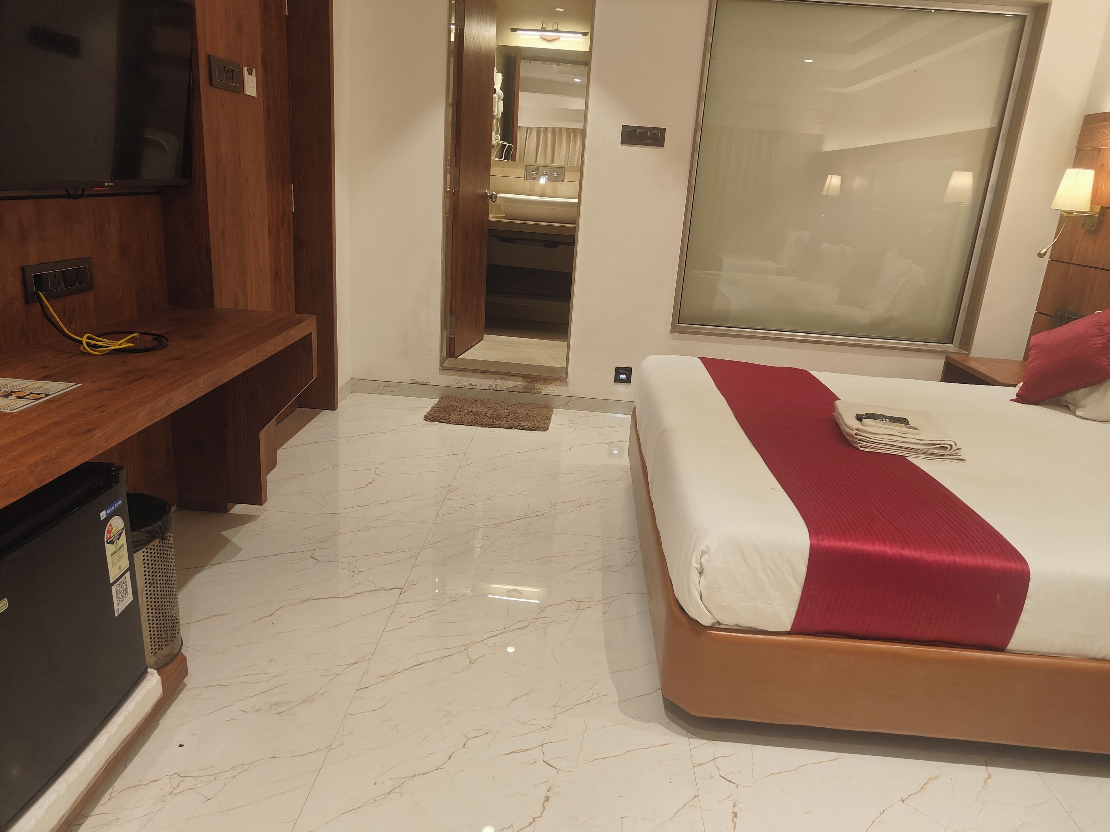A hotel room with a bed, a desk, a television, and a mirror.