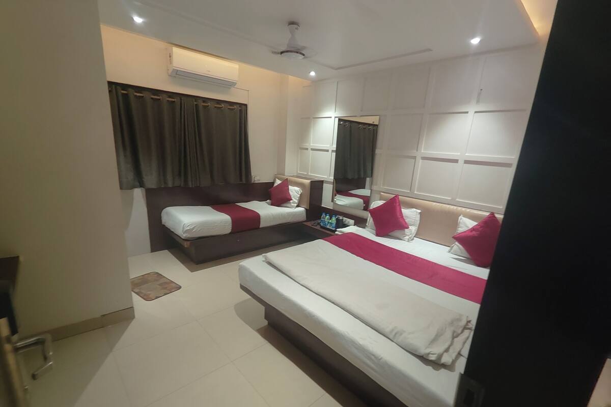 Habitación de hotel con dos camas, un espejo grande y un equipo de aire acondicionado.
