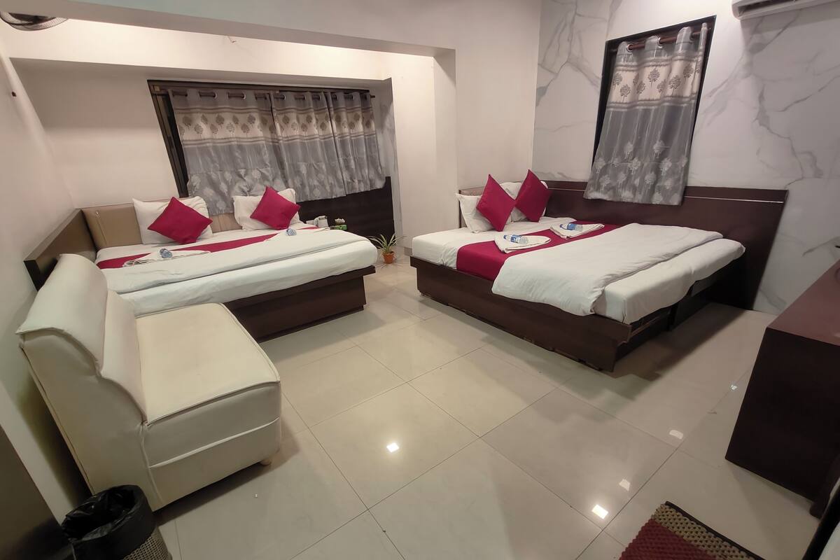 Habitación de hotel con dos camas, un sofá, un cubo de basura y una alfombra pequeña.