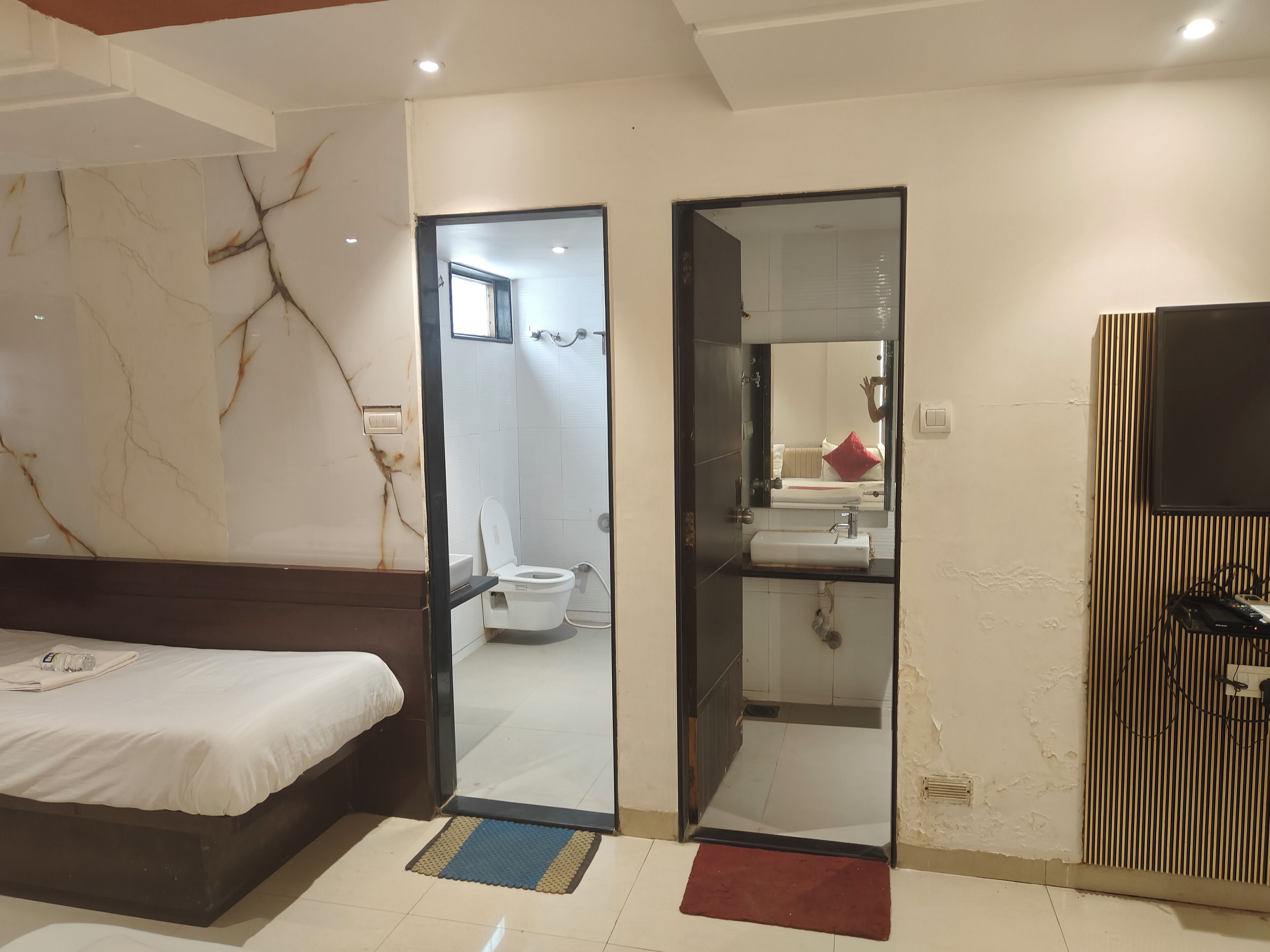 A bedroom with a bed, a bathroom with a toilet, and a mirror.