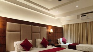 A hotel room with two beds, a wooden headboard, a wall-mounted lamp, and an air conditioning unit. - Hotel Anand Palace (Rahata)