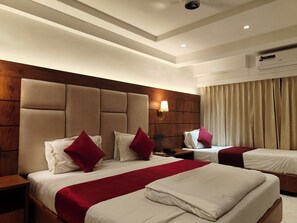 Habitación de hotel con dos camas, cabecero de madera, lámpara de pared y equipo de aire acondicionado.