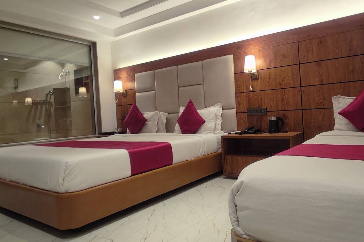 Una habitación de hotel con dos camas, cabeceros de madera y mesitas de noche con lámparas.