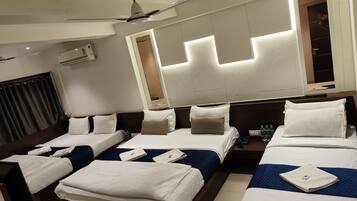 A hotel room with two beds, a ceiling fan, a mirror, and a window with curtains.