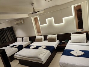 Une chambre d’hôtel avec deux lits, un ventilateur de plafond, un miroir et une fenêtre avec des rideaux.