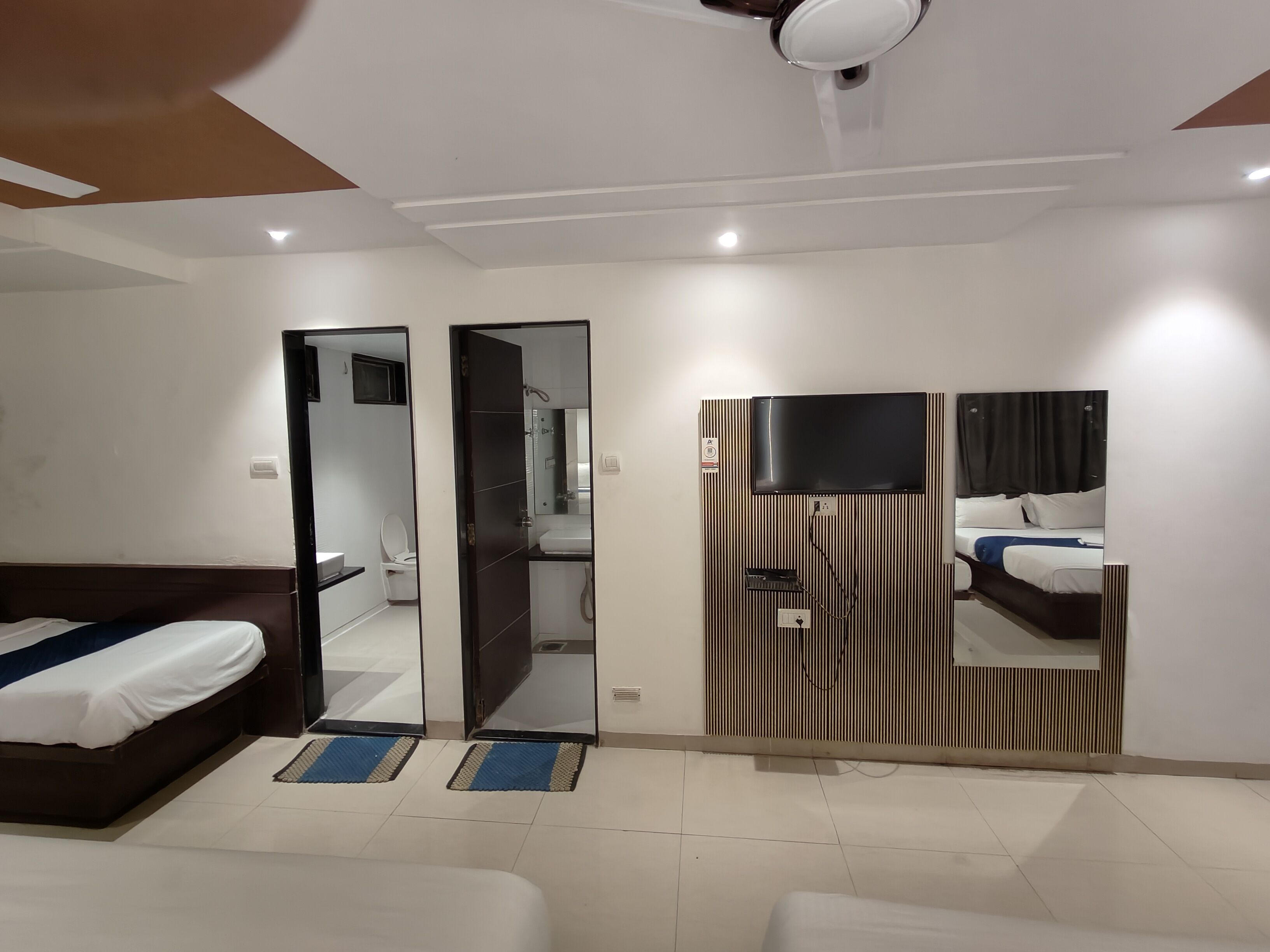 Una habitación de hotel con una cama, un televisor montado en la pared y un espejo.