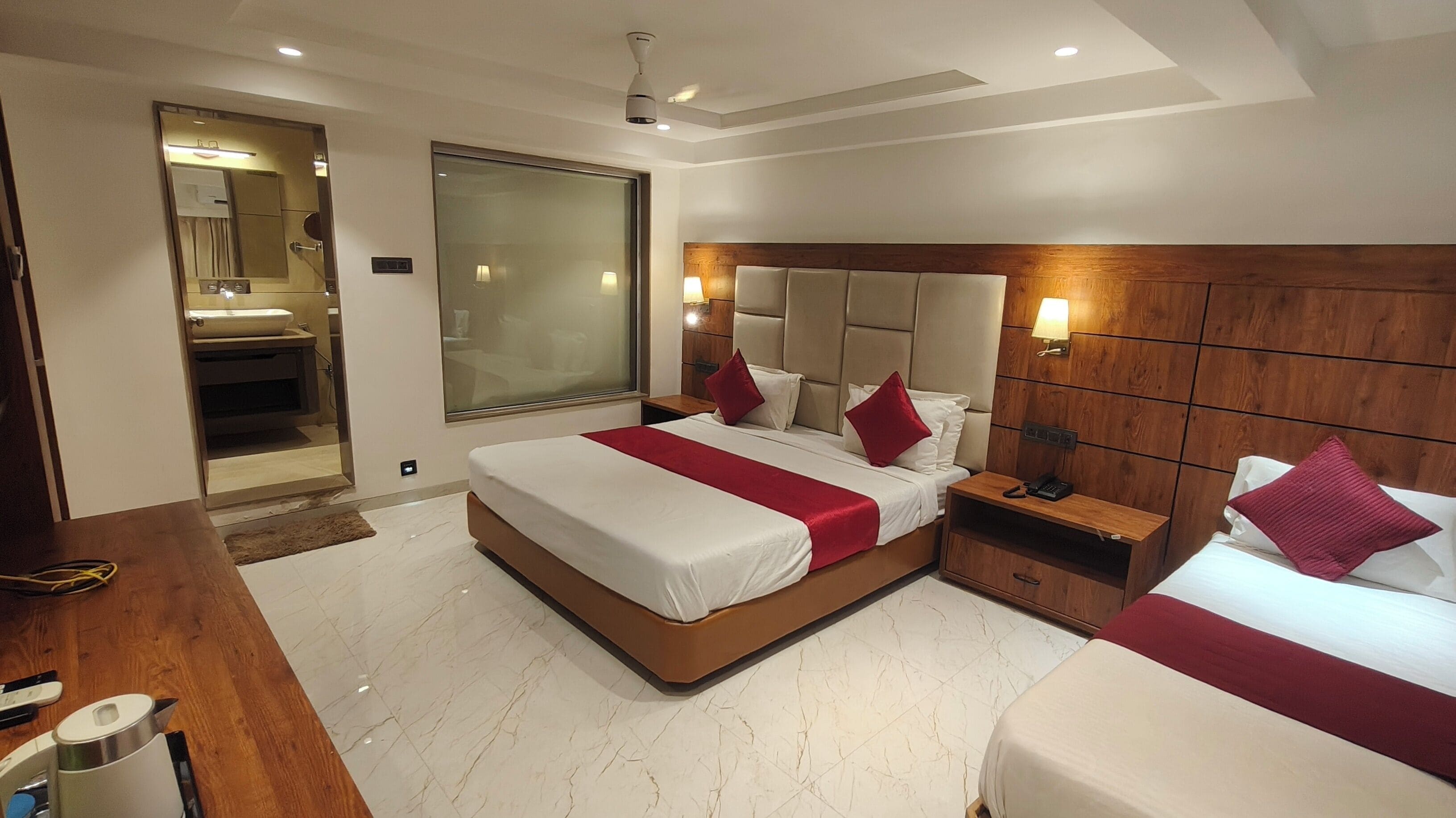 A modern hotel room with a large bed, bedside tables, a mirror, and a glass-enclosed shower area.