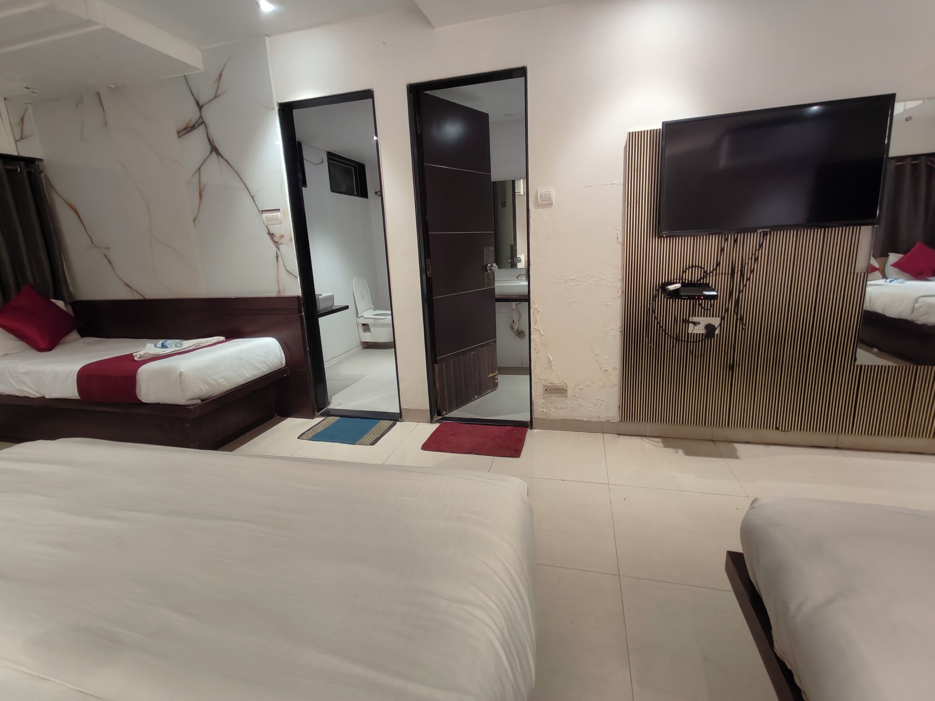Une chambre d’hôtel avec deux lits, une télévision, un miroir et une armoire.