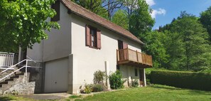 A two-story house with a balcony, a garage, and a well-maintained garden.