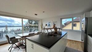 Eine moderne Küche mit einer zentralen Kochinsel, großen Fenstern und Seeblick.
