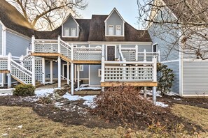 A two-story house with a wooden deck, a front porch, and a small garden area with some snow. - Lovely Norwich Villa, On Golf Course w/ Amenities! (Norwich)