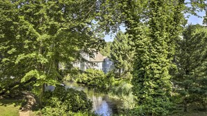 A serene lakeside view with a house surrounded by lush greenery and trees.