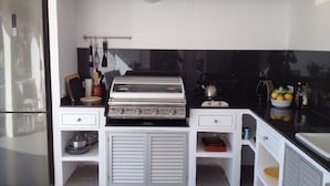 A compact kitchen with a built-in stove, a refrigerator, and white cabinetry. - Spacious apartment with large terrace and summer kitchen (Port de Sóller)