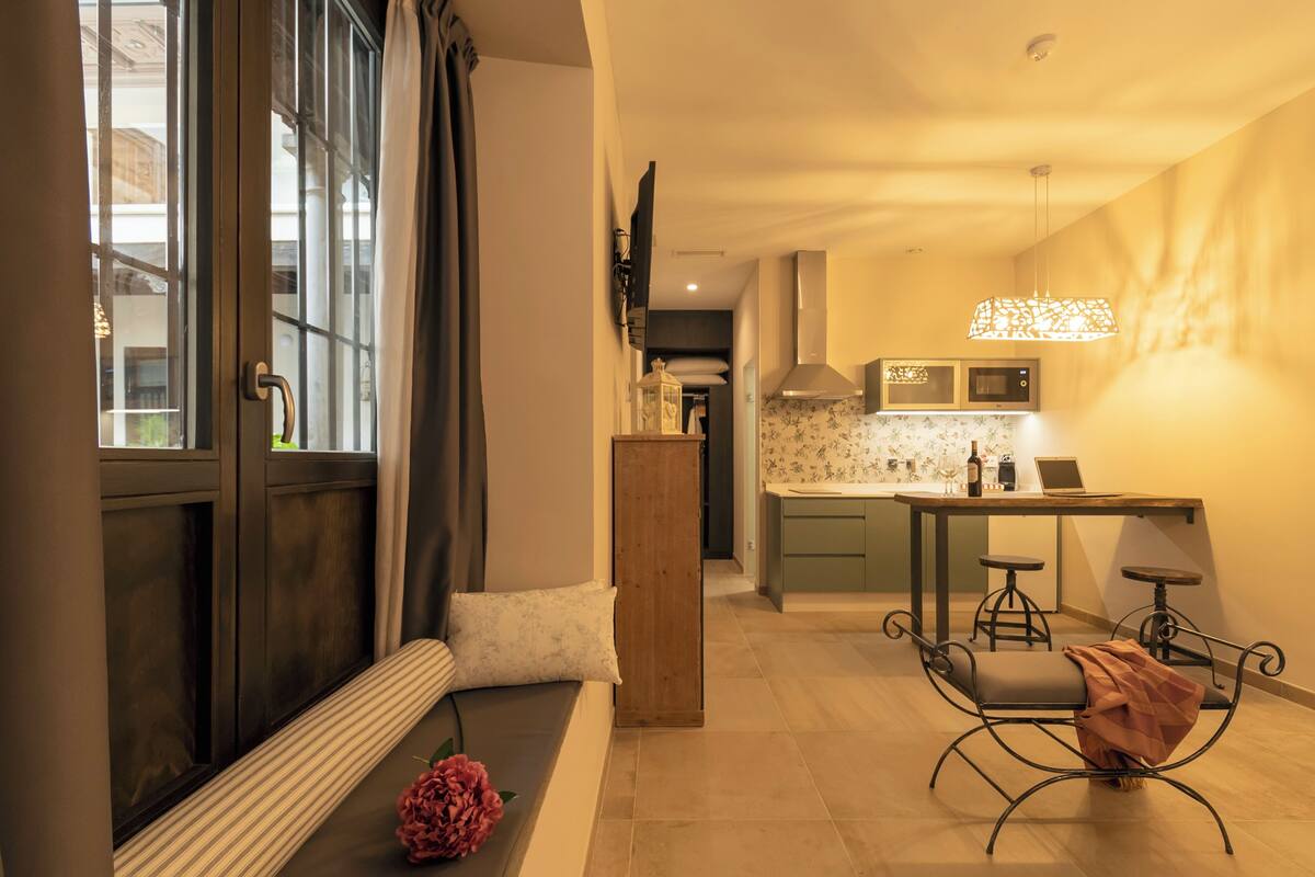 Una cocina moderna con comedor, un banco de madera y vistas por una ventana.