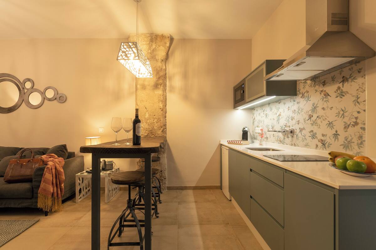 Cocina compacta con comedor, pared de acento de piedra y un revestimiento de papel tapiz con motivos florales.