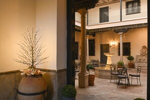 A courtyard with a fountain, potted plants, and outdoor seating. - Palacete 1620, Apartamentos Premium-Only adults (Granada)