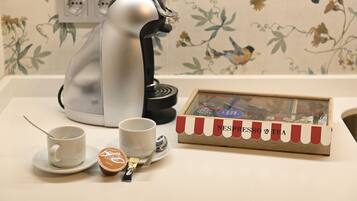 Una cafetera, dos tazas, una cuchara, un recipiente pequeño y una caja con la etiqueta 'NESPRESSO & TEA' sobre una mesa.