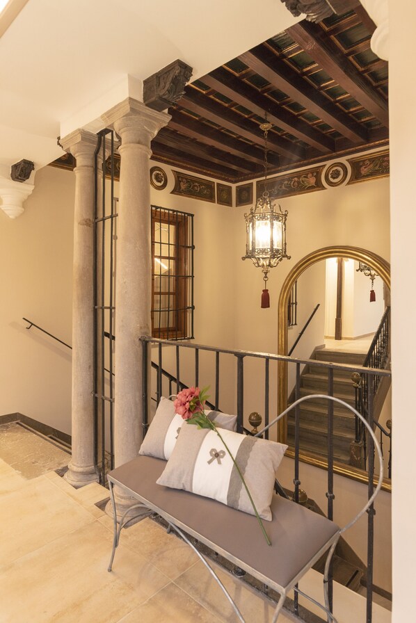 A staircase with a bench, a chandelier, and a mirror. - Palacete 1620, Apartamentos Premium-Only adults (Granada)