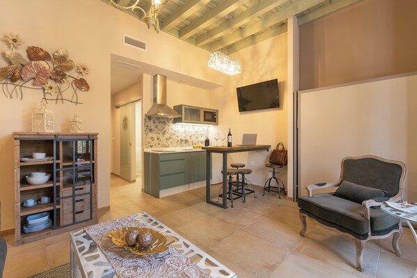 Una cocina moderna con una isla central, una zona de comedor con mesa y sillas, y un área de estar con sofá y sillones.