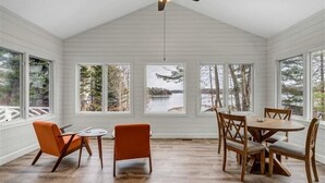 A dining area with a wooden table and chairs, large windows with a view of trees and a body of water, and a ceiling fan. - 4 Bedrooms, 1 Flex Room, 4 Bathrooms!  Beautiful Home with SANDY BEACH!  Occupancy 8! HOT TUB! (Huddleston)