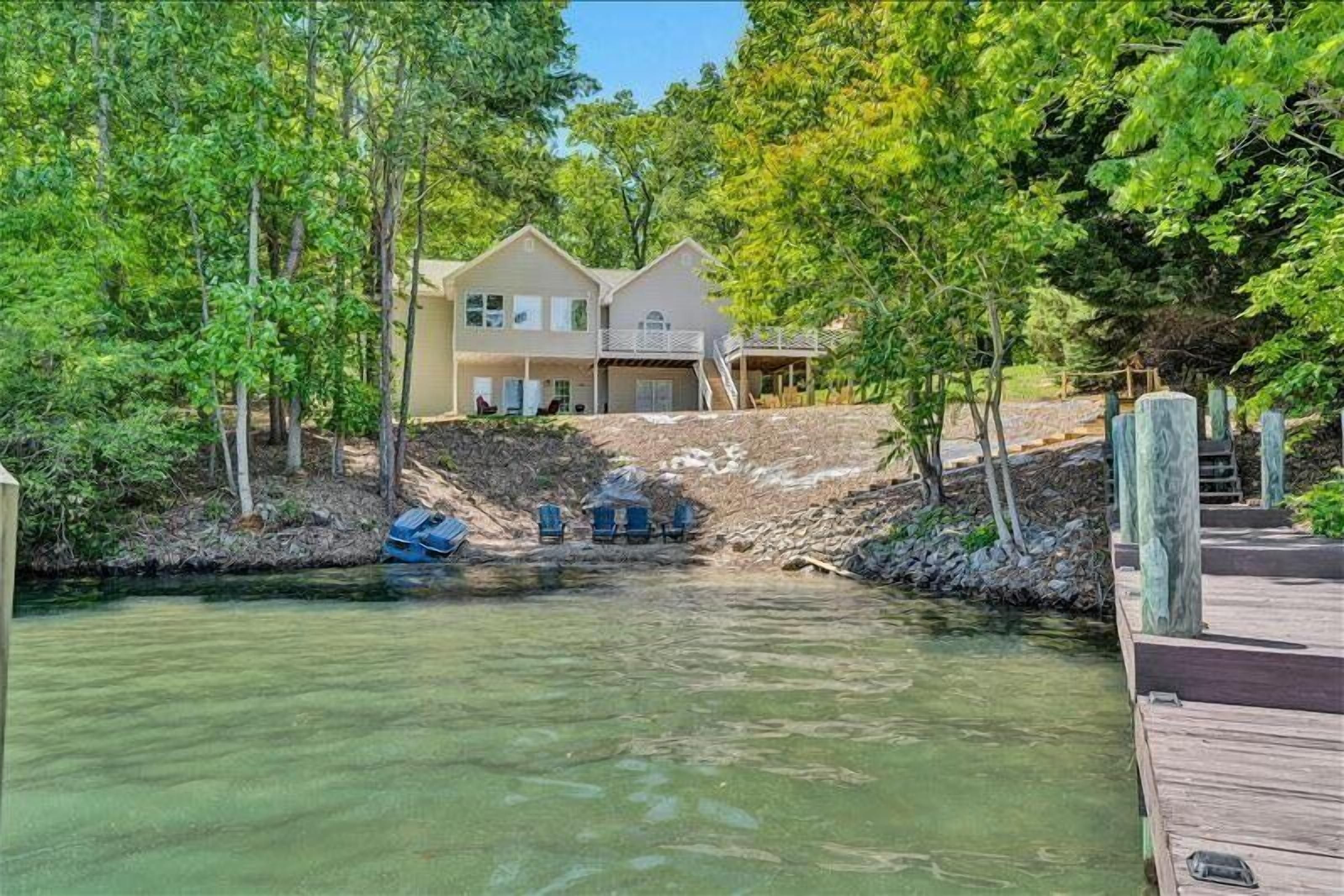 A house with a dock extending into a river, surrounded by trees.