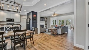 A spacious kitchen with modern appliances, a dining area with wooden chairs, and a living room with a sofa and coffee table. - 4 Bedrooms, 1 Flex Room, 4 Bathrooms!  Beautiful Home with SANDY BEACH!  Occupancy 8! HOT TUB! (Huddleston)