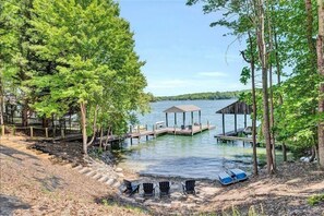 A lakeside property with a dock, outdoor seating, and a covered area.