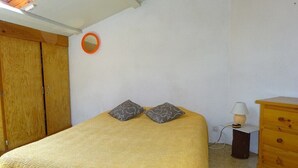 A bedroom with a bed, a wooden wardrobe, a nightstand with a lamp, and a dresser. - Semi-detached duplex house of 50m² for 5 people (BISCARROSSE)