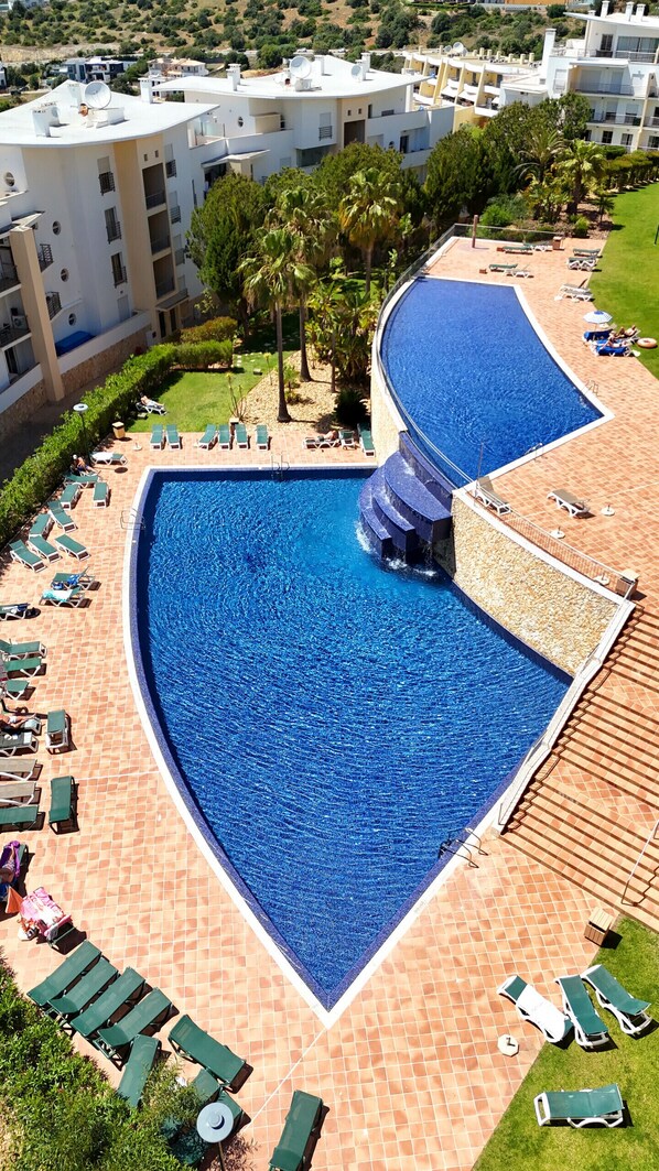A large, kidney-shaped swimming pool with multiple sun loungers and a small slide.